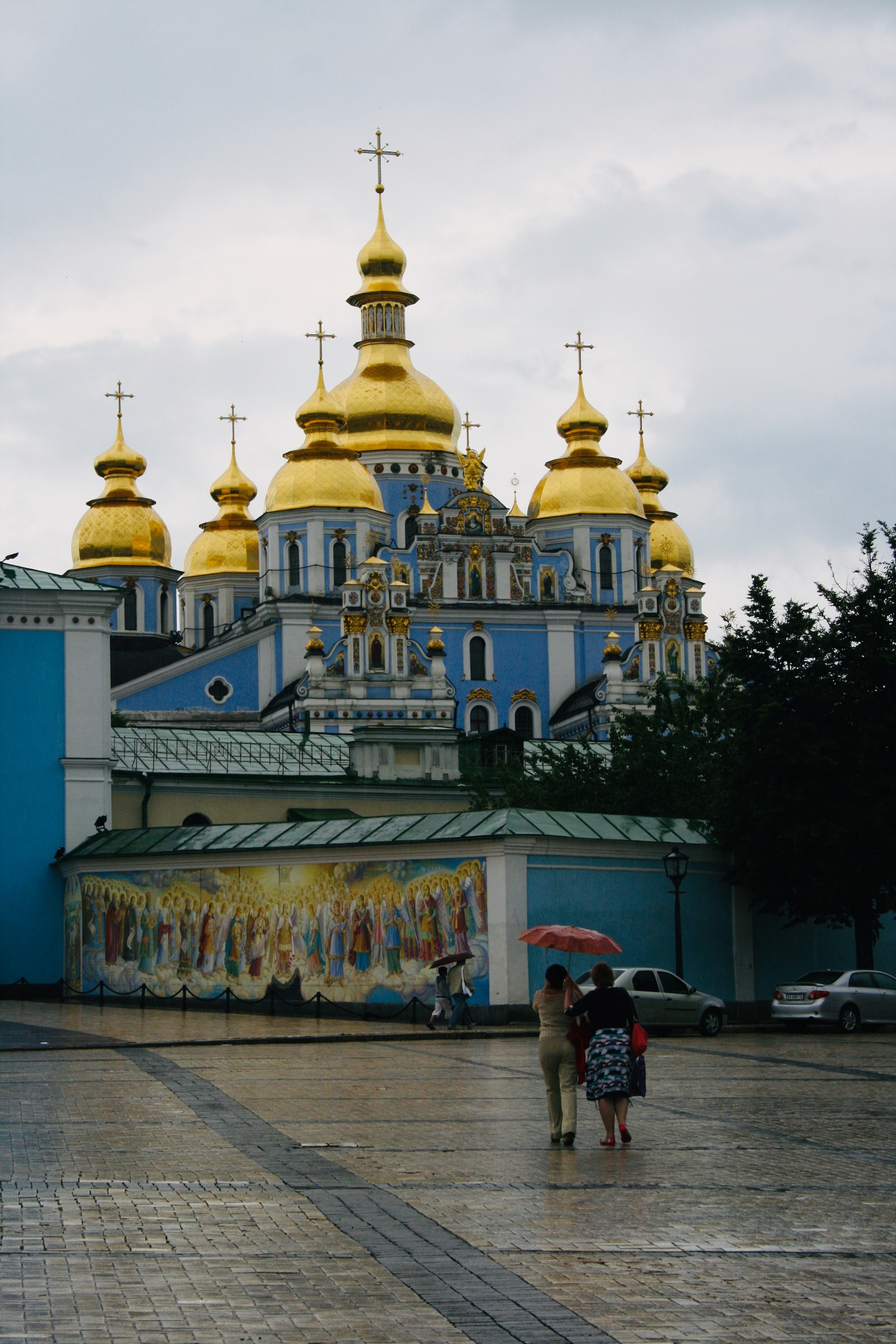 a group of people walking in front of St. Michael's Golden-Domed Monastery with gold domes