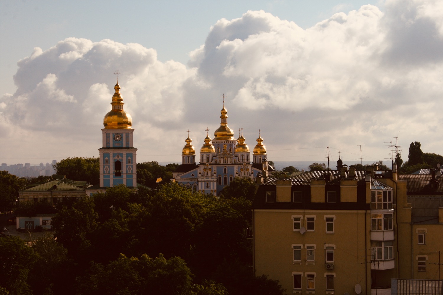 a building with gold domes and a tower with trees
