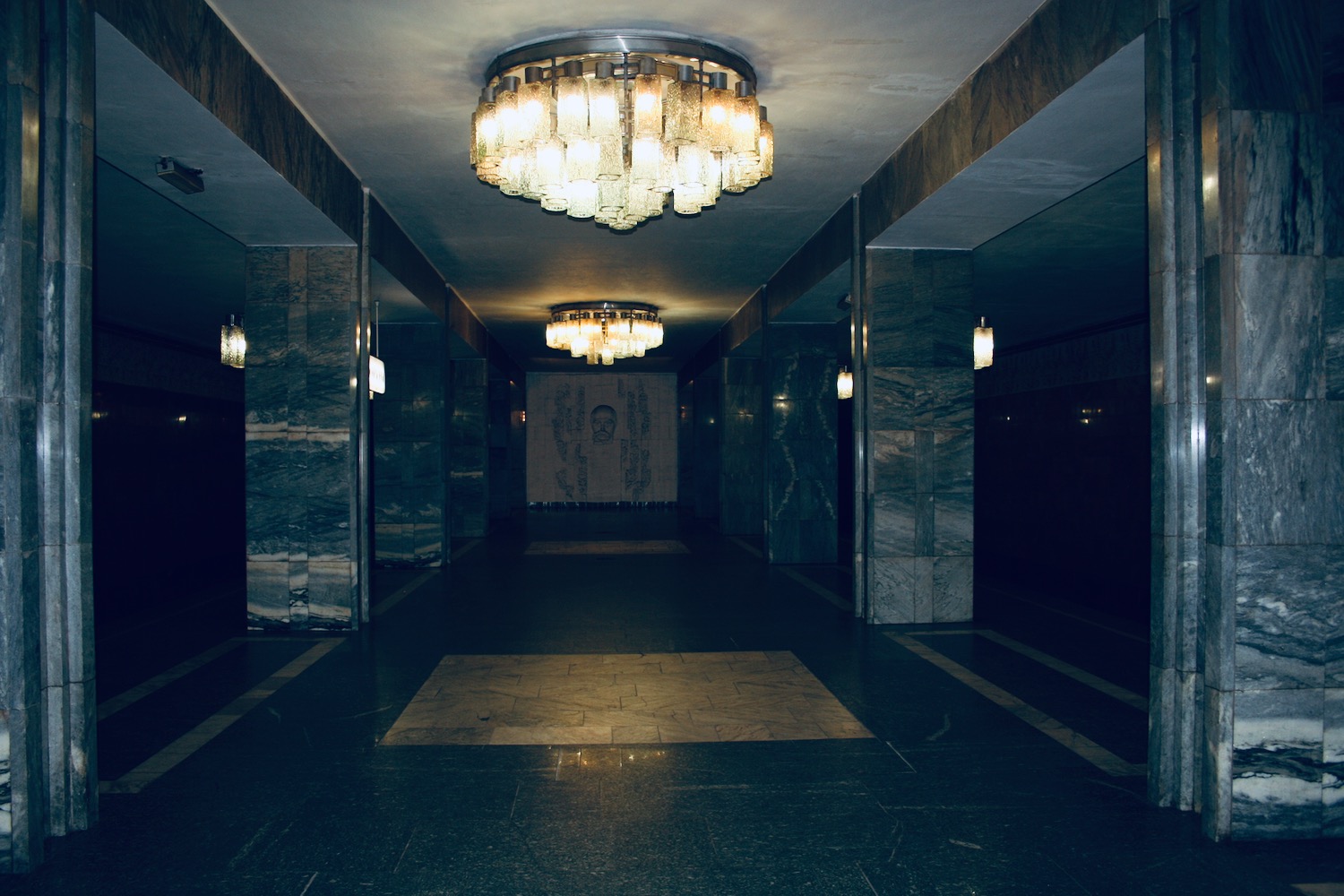 a hallway with a chandelier and marble walls