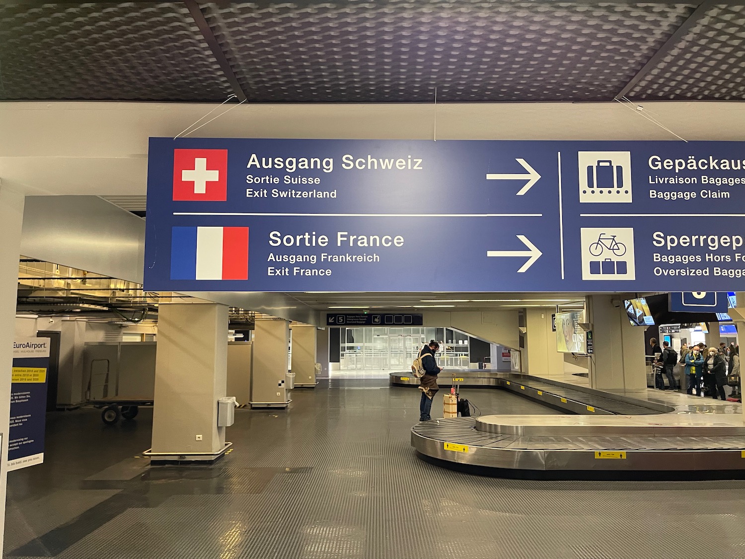 a sign with a person standing in front of a luggage carousel