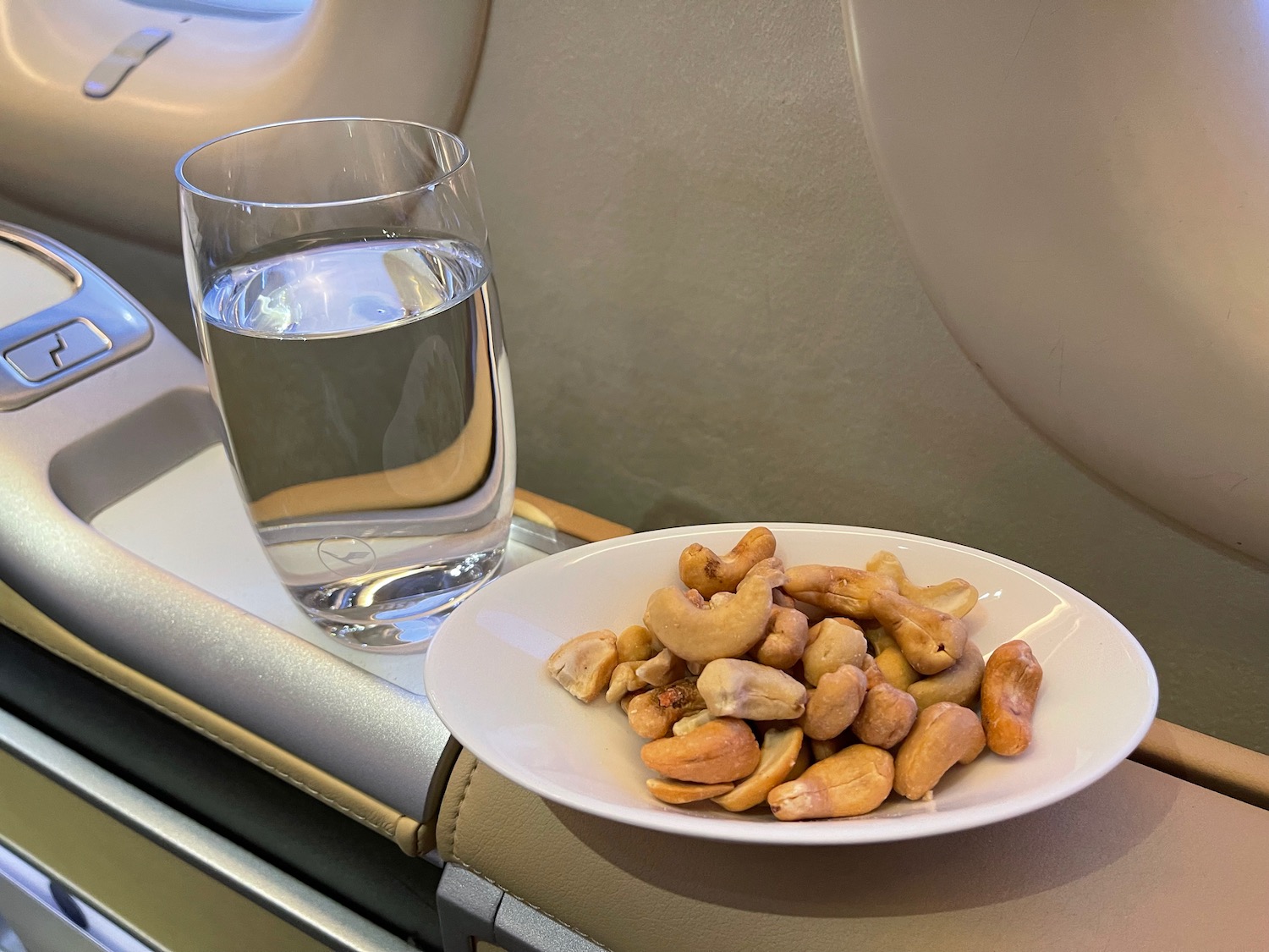 a plate of cashews and a glass of water on a plane