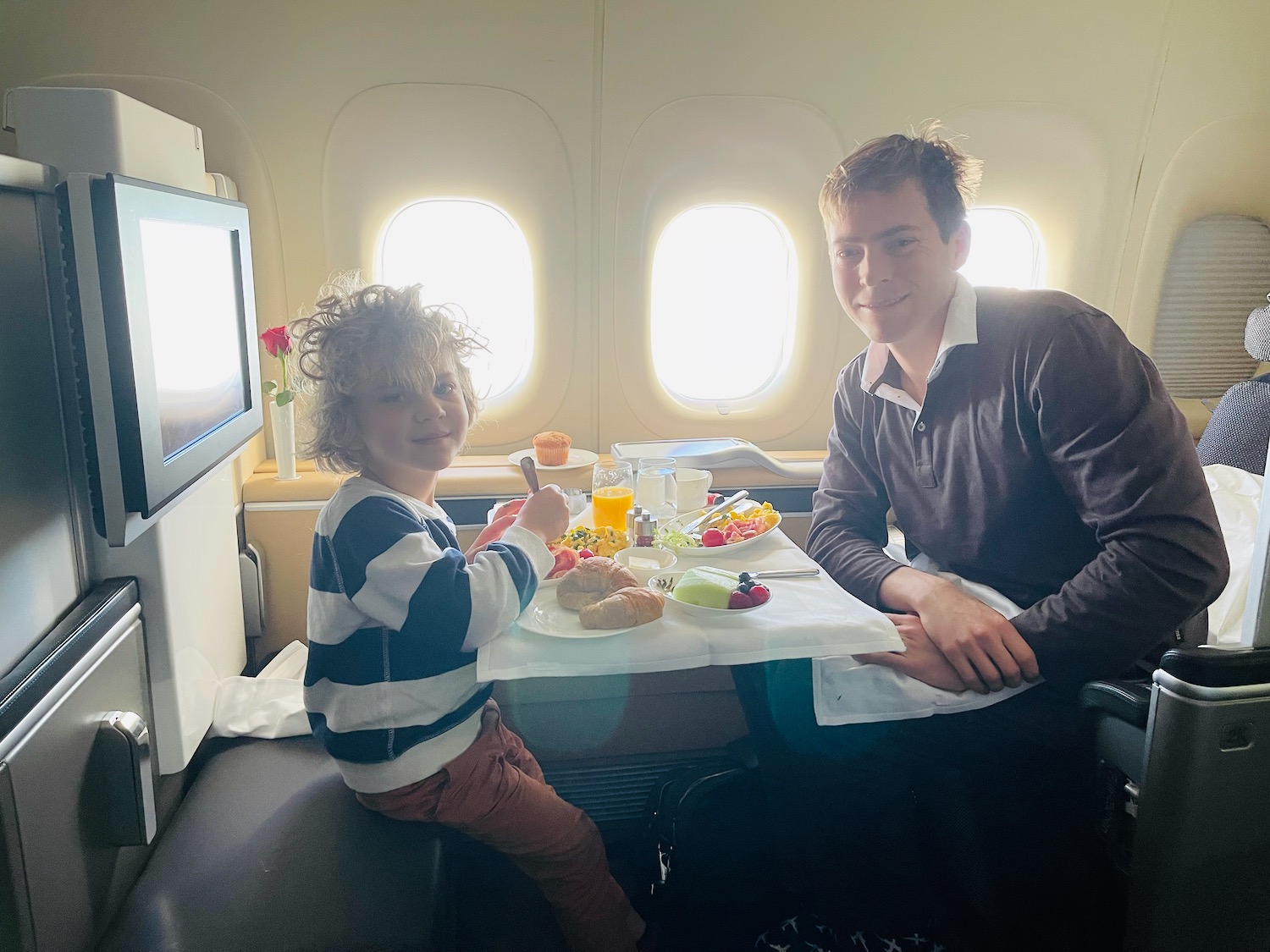 a man and child sitting at a table in an airplane