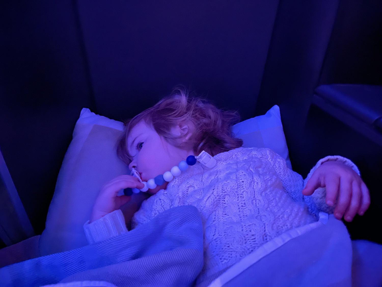 a child lying in a bed with a pacifier in her mouth