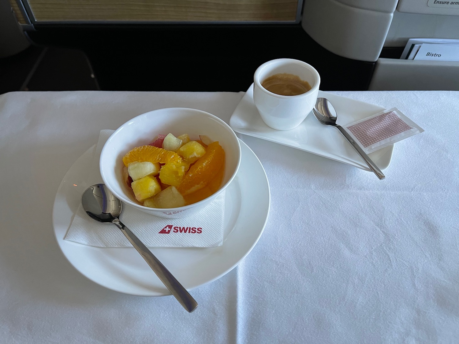 a bowl of fruit and a cup of coffee on a table