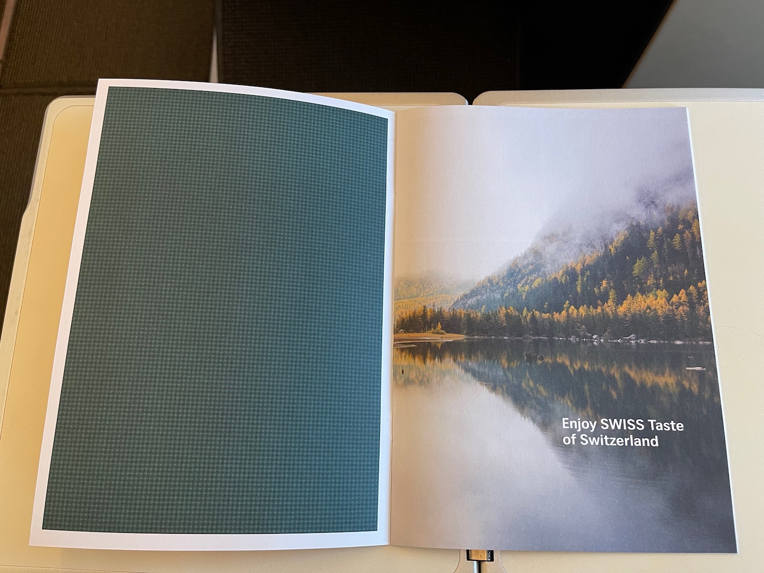 an open book with a picture of a lake and trees