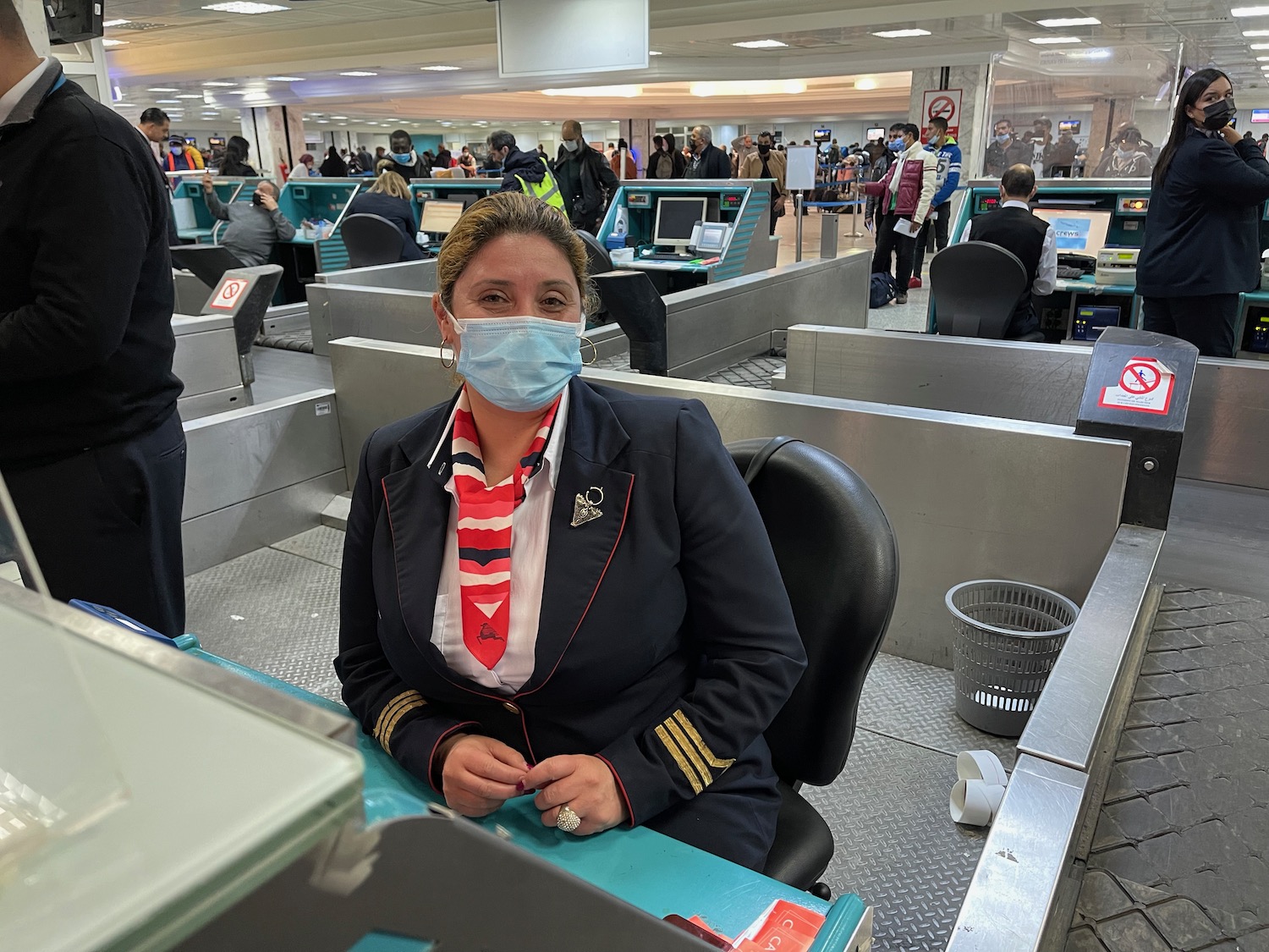 a woman wearing a mask sitting at a desk in an airport