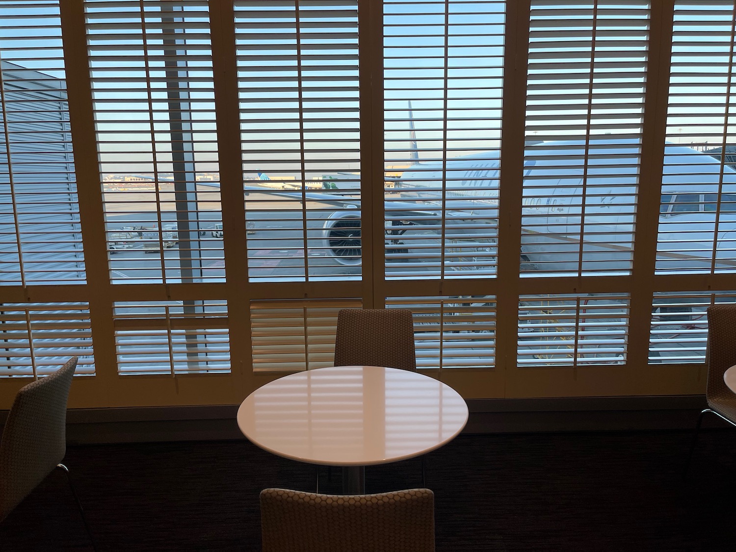 a table and chairs in front of a window with blinds