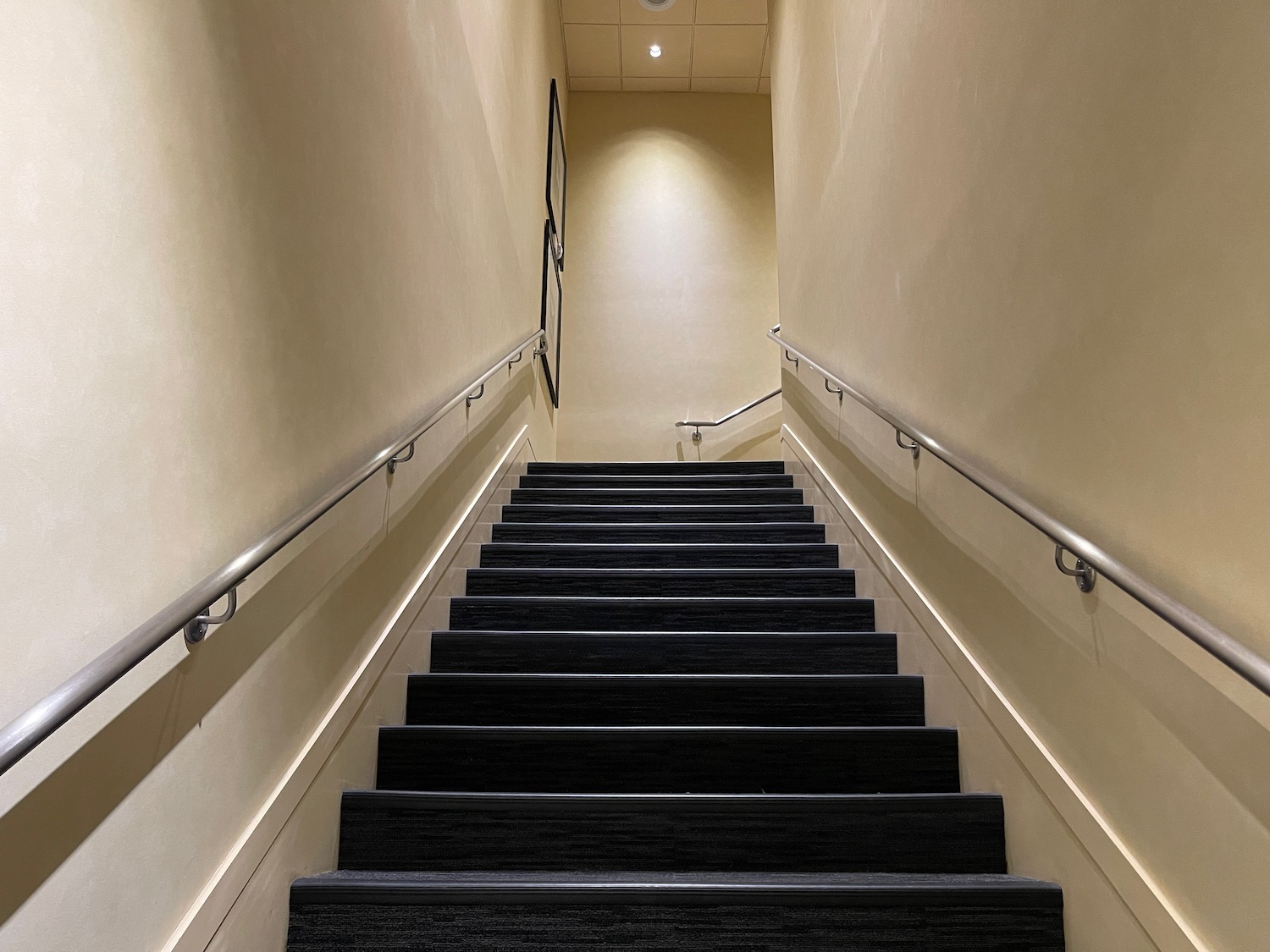 a staircase with handrails and a light on the wall