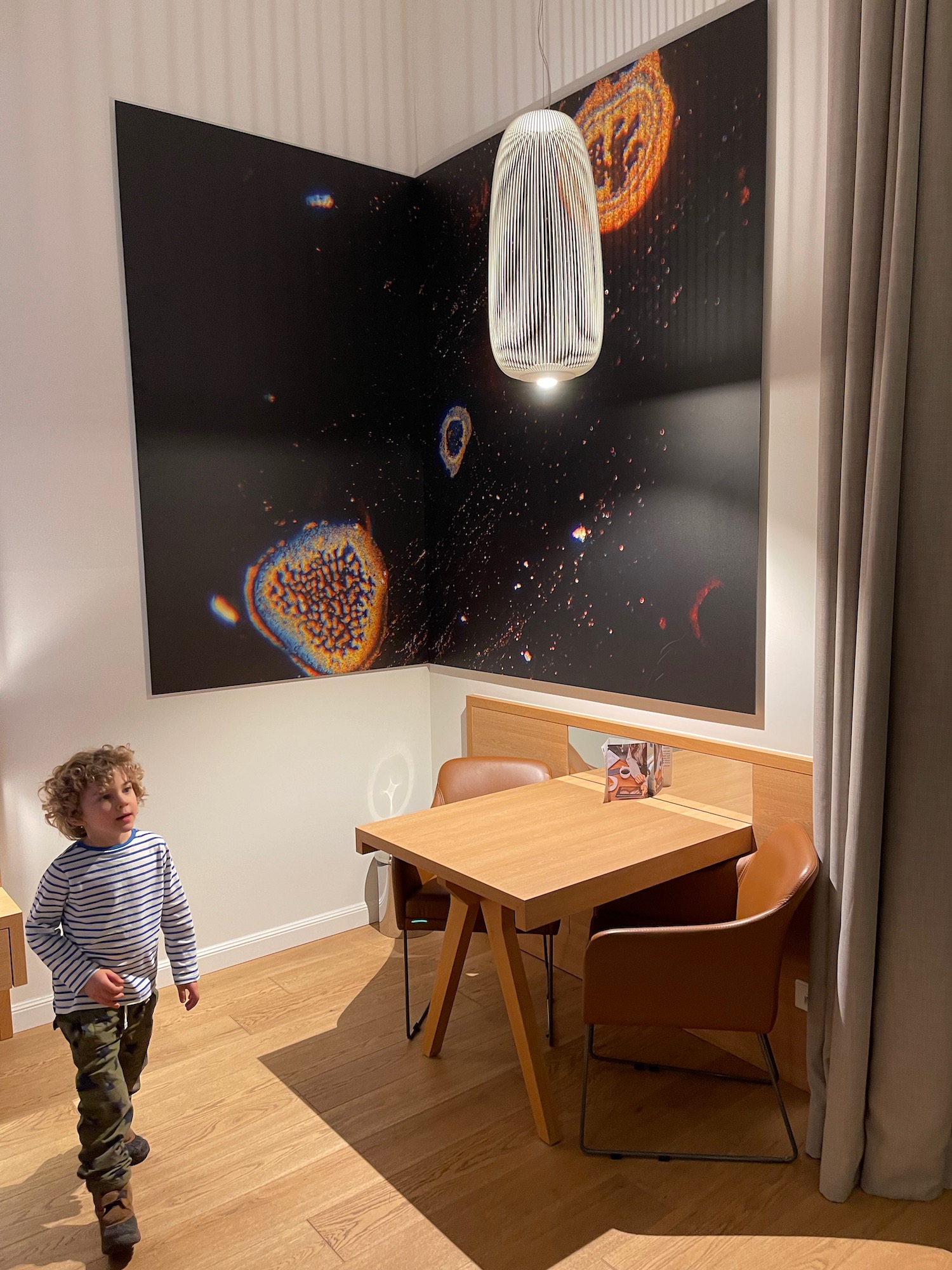 a child standing in a room with a table and chairs