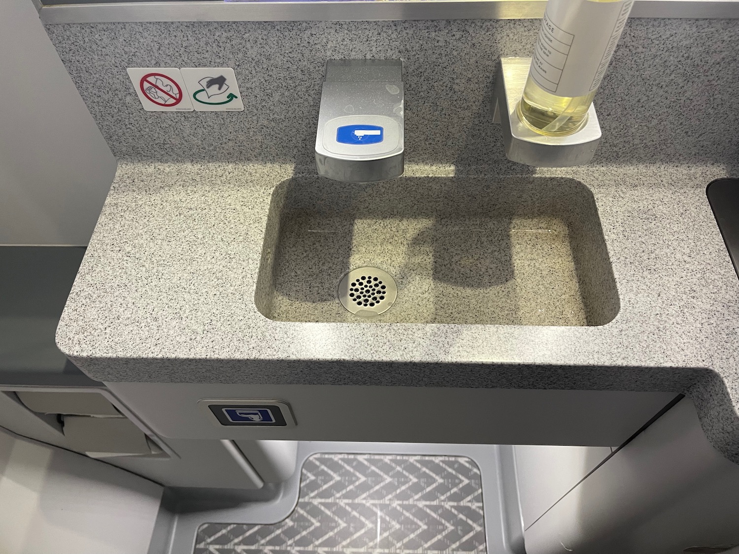 a sink with soap dispenser and a bottle of liquid