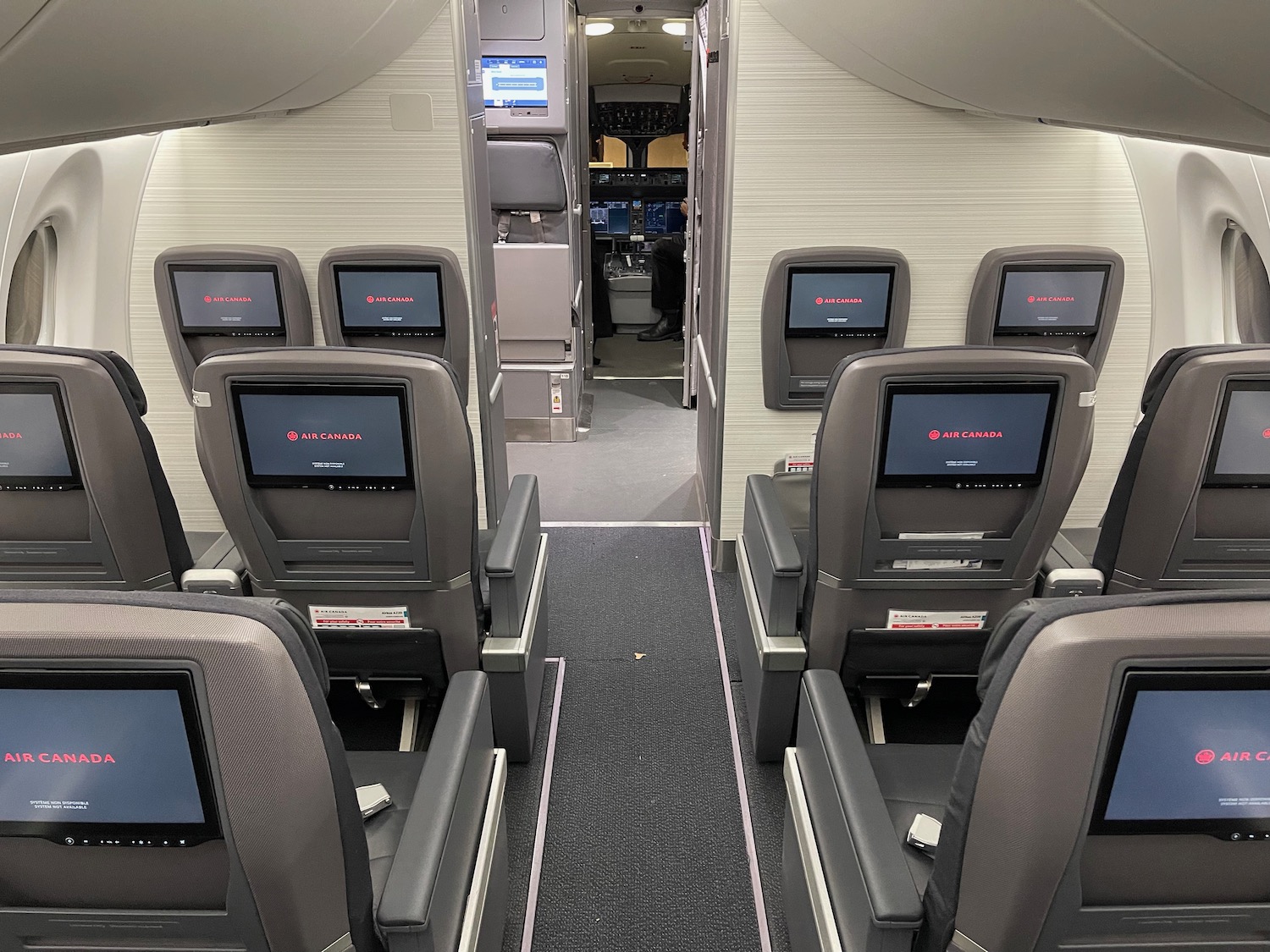 the inside of an airplane with seats and monitors