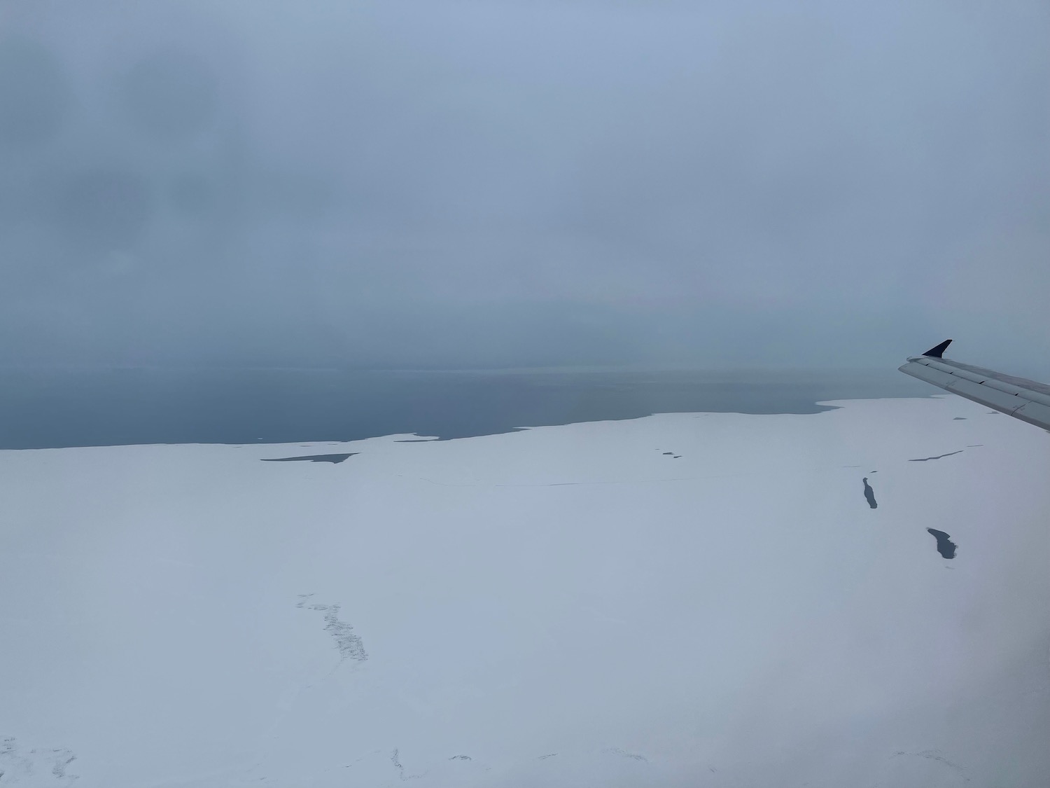 a snow covered ground with a body of water in the background