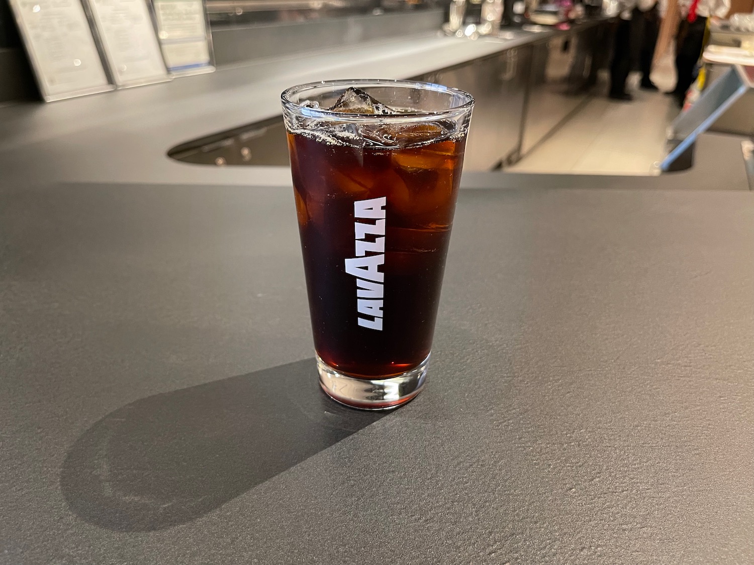 a glass of cola with ice on a counter