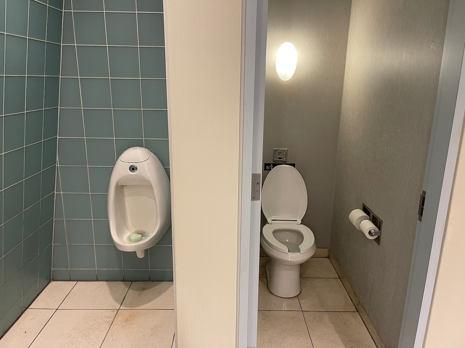 a bathroom with a urinal and a wall