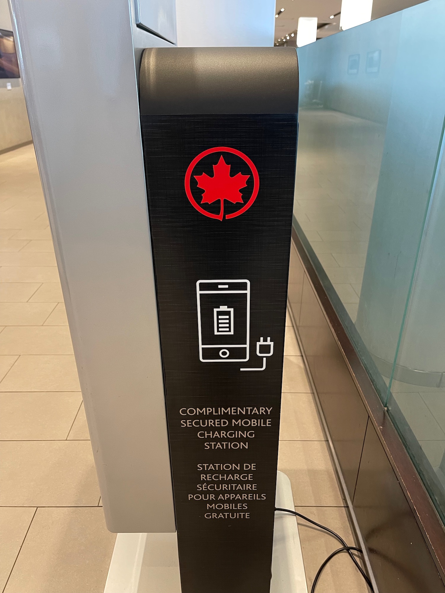 a black rectangular sign with a red leaf and a red maple leaf on it