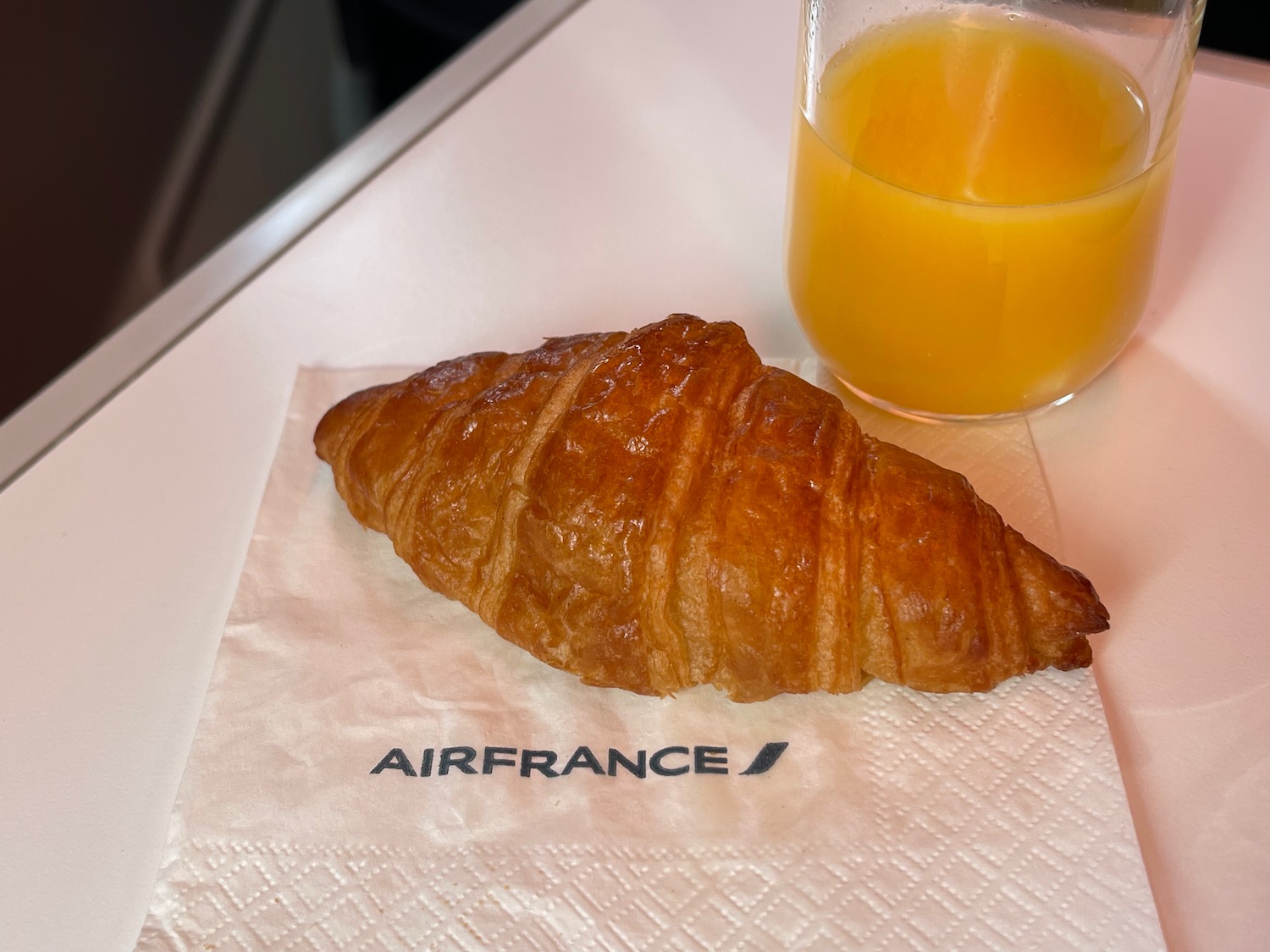 a croissant and a glass of orange juice on a napkin