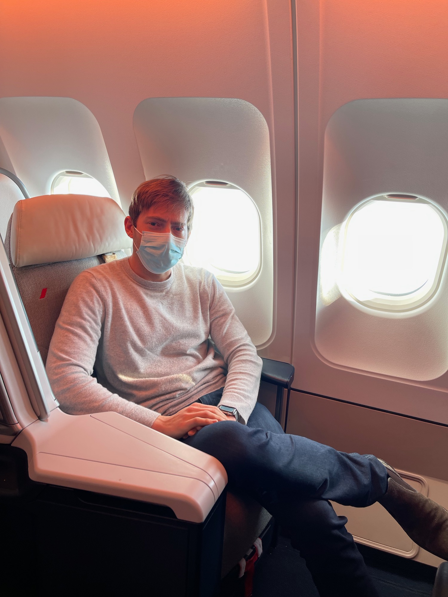 a man wearing a face mask sitting in an airplane