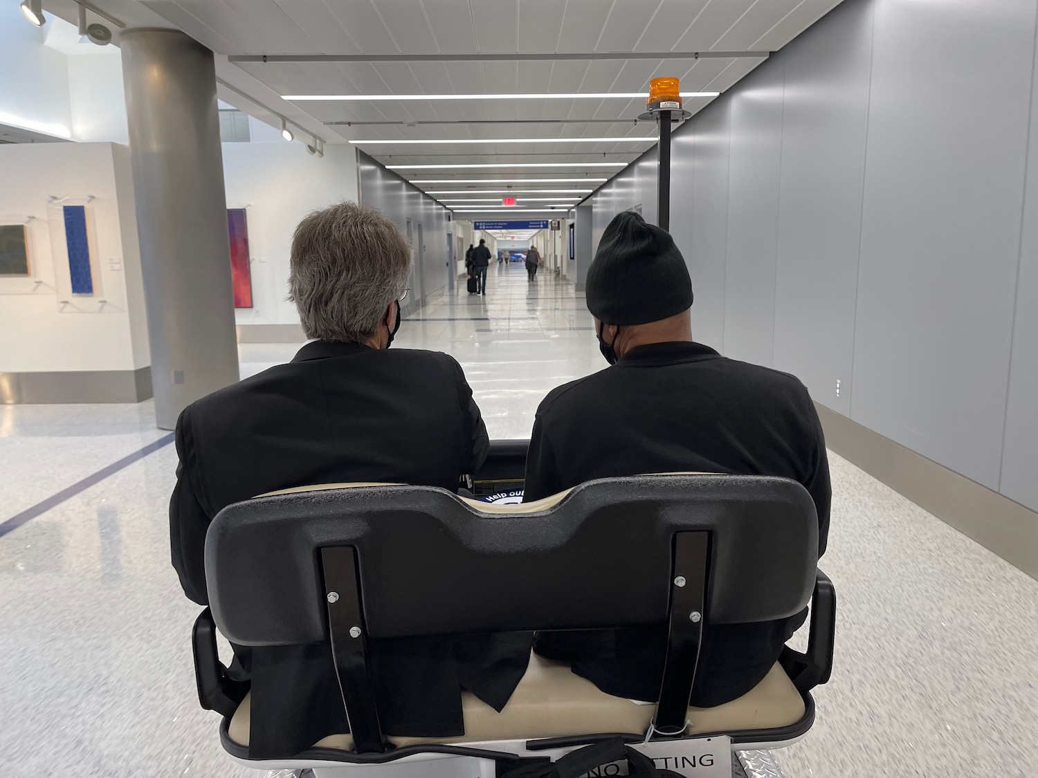 two men sitting in a wheelchair in a hallway