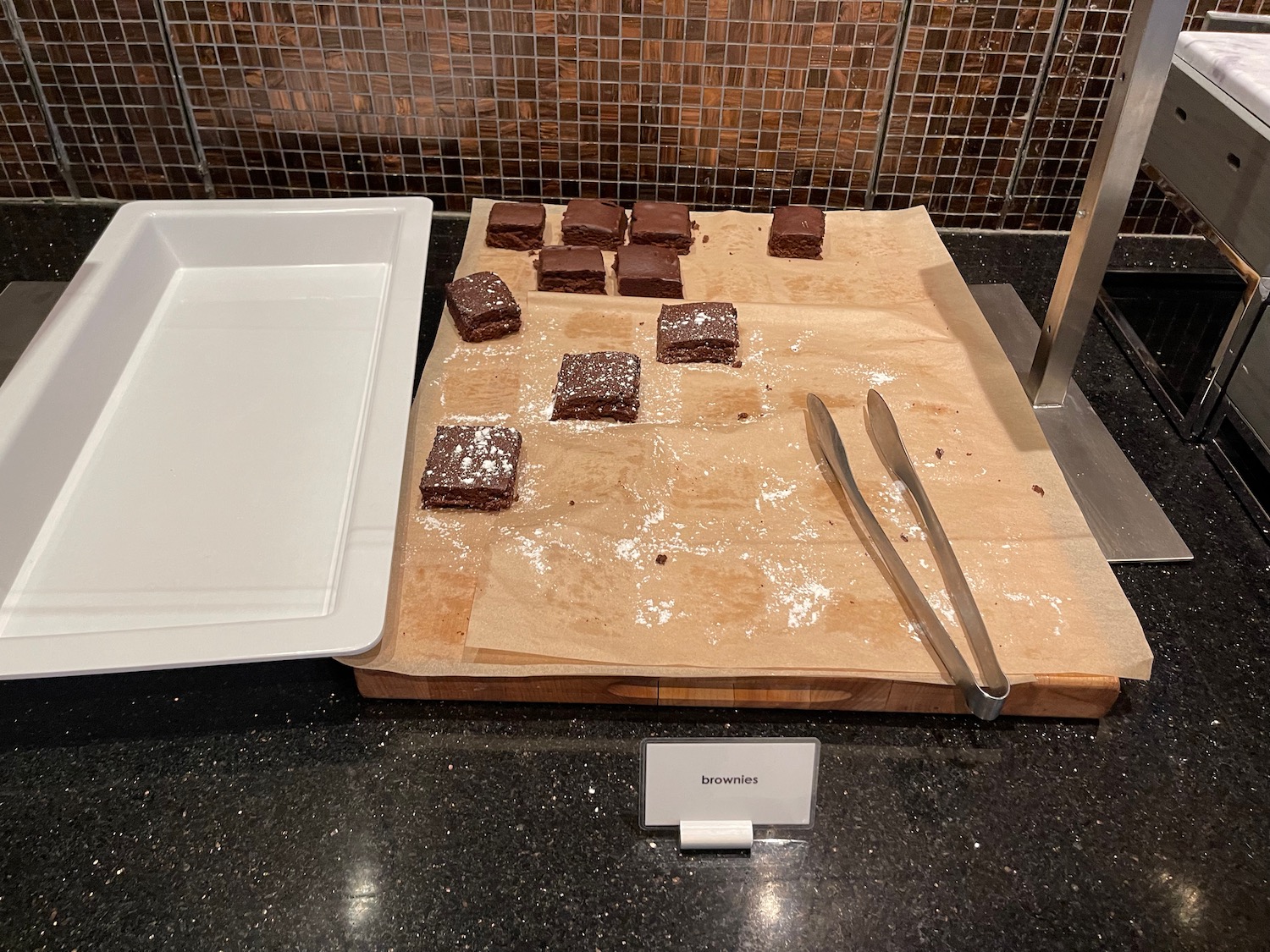 brownies on a cutting board with a tray of food