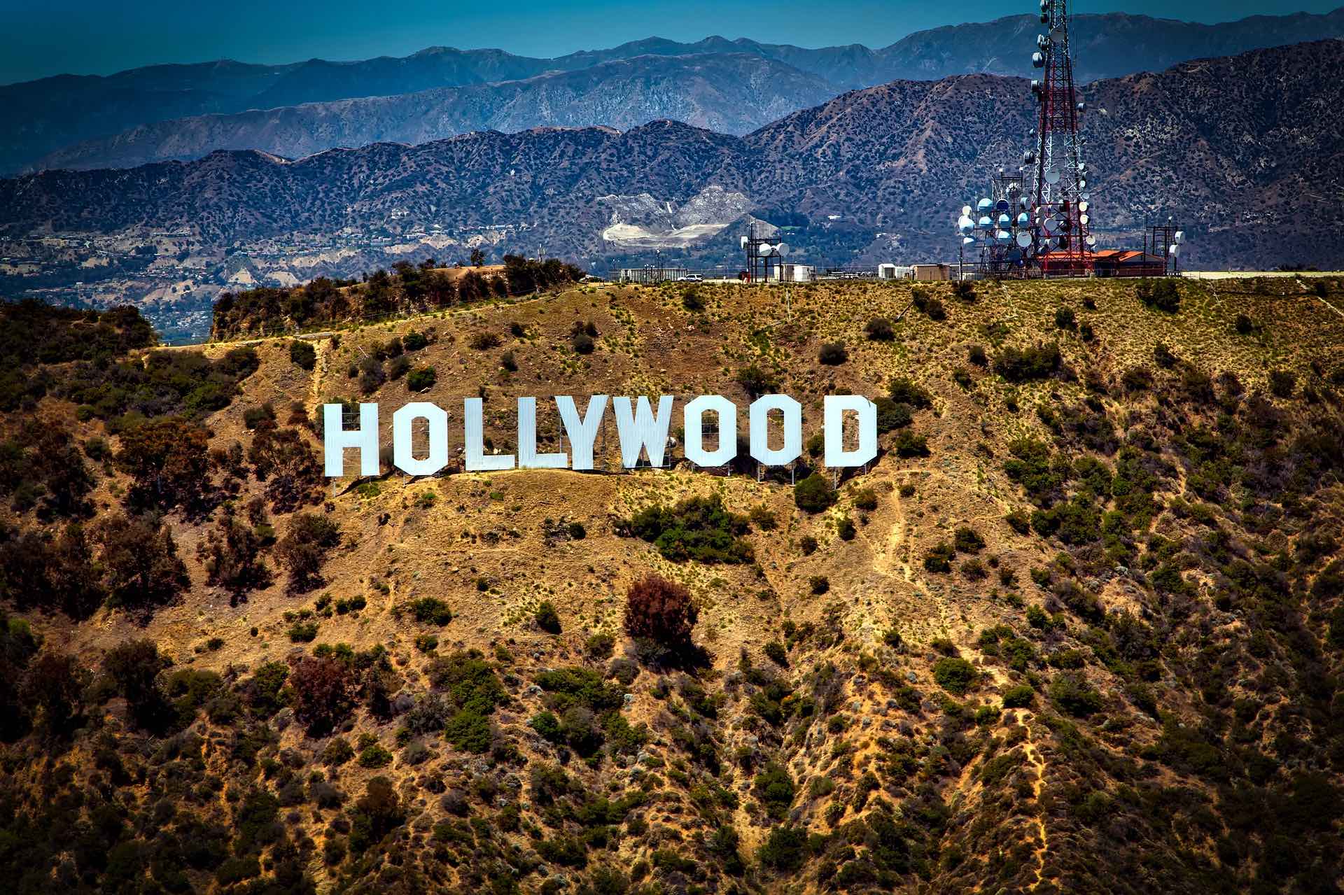 a large white sign on a hill with Hollywood Sign in the background