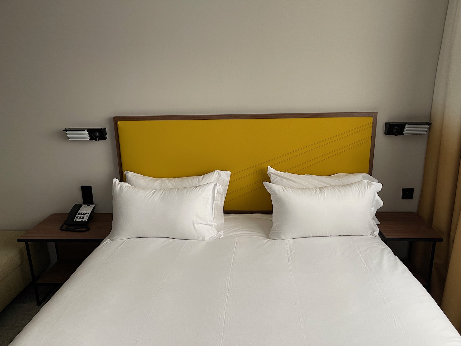 a bed with white sheets and a yellow headboard