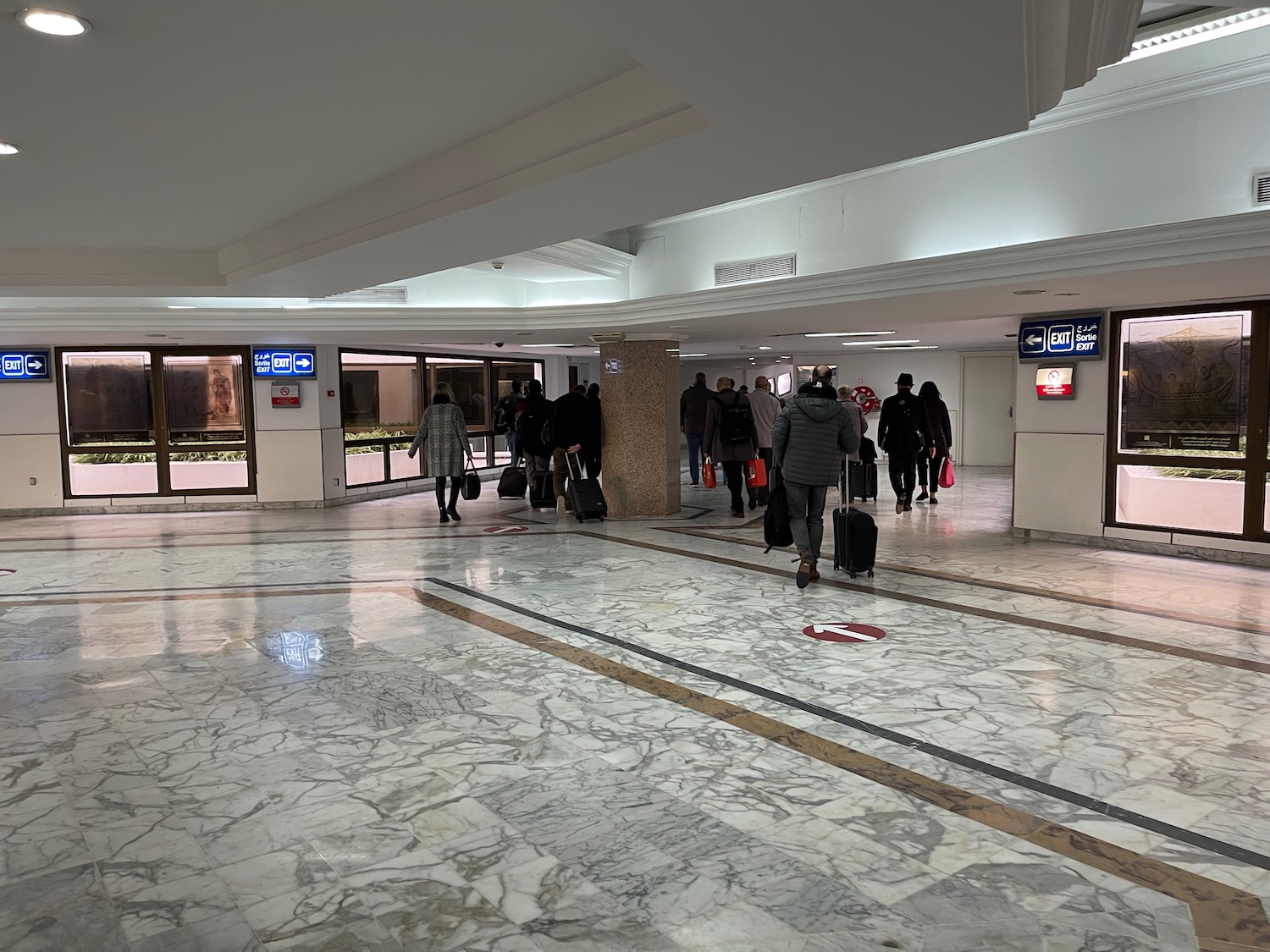 a group of people walking in a large room with marble floor