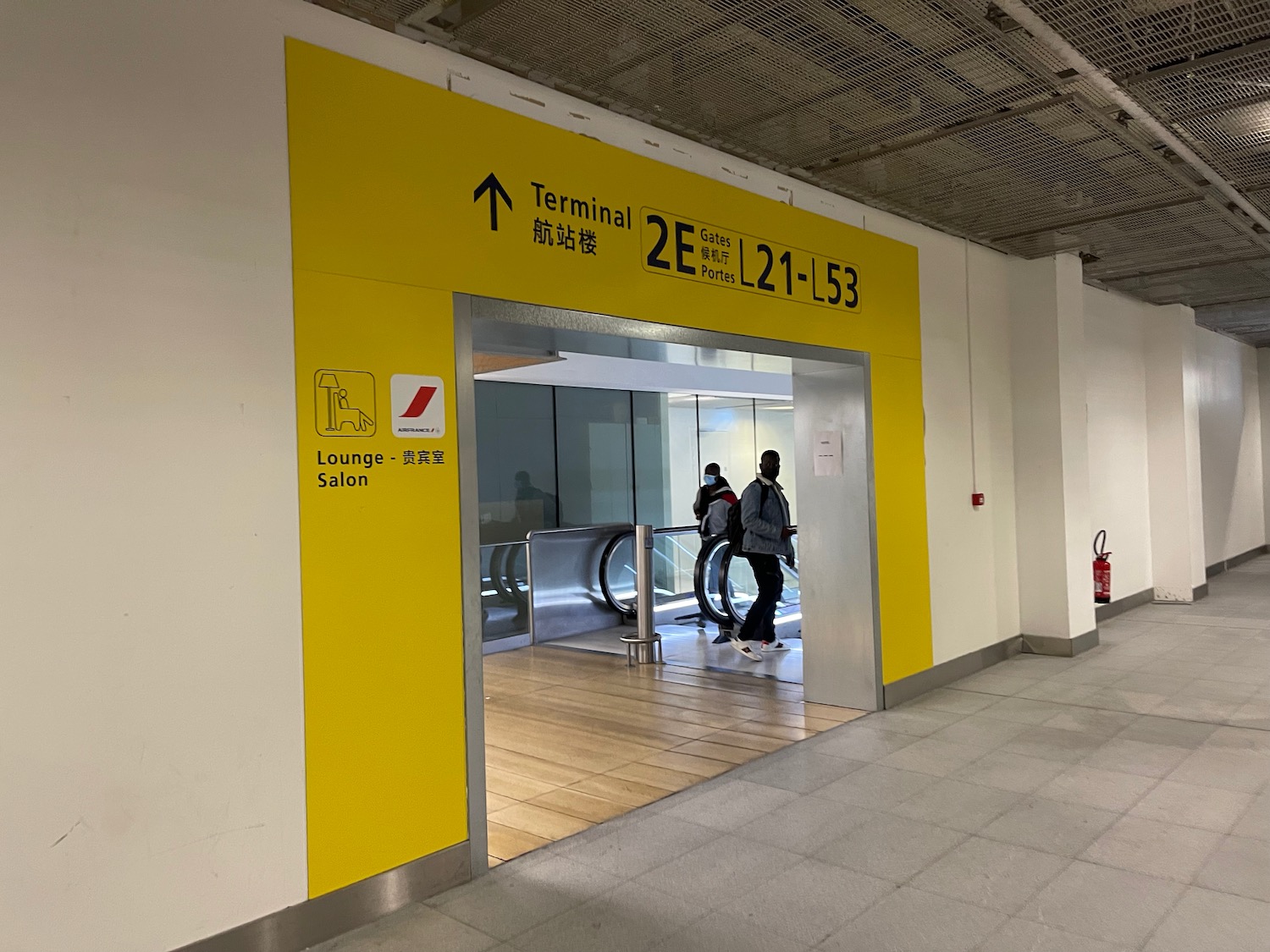 people in an airport with a yellow sign