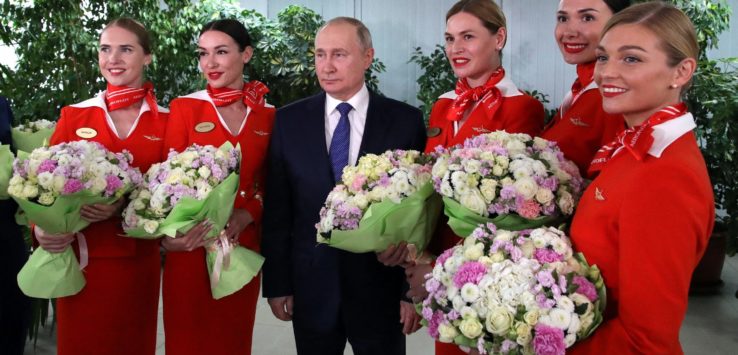 a man in a suit and tie with a group of women in red uniforms