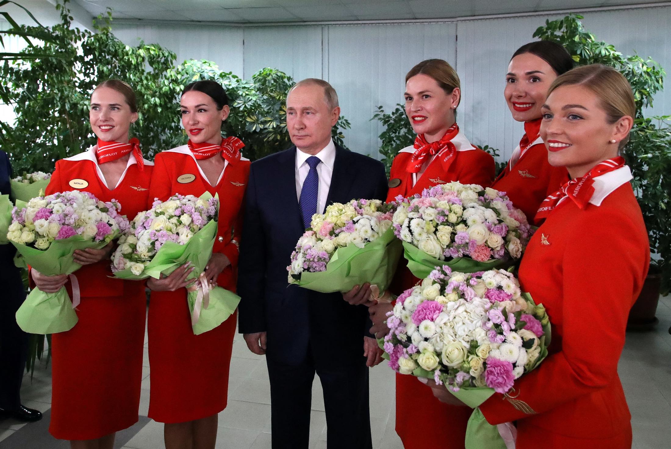 a man in a suit and tie with a group of women in red uniforms