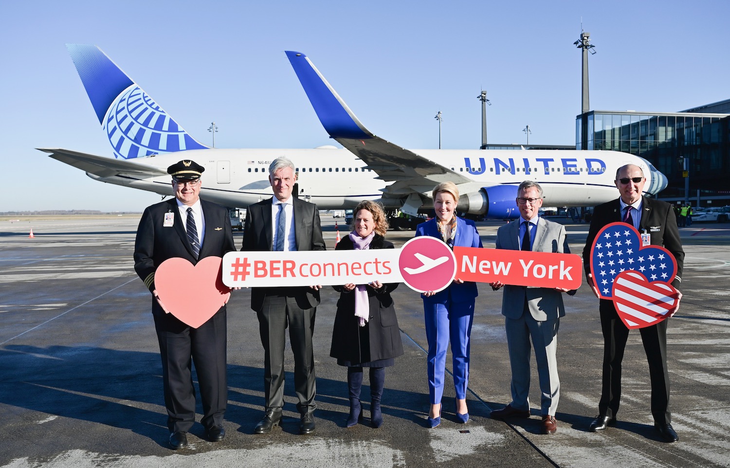 a group of people holding signs in front of an airplane