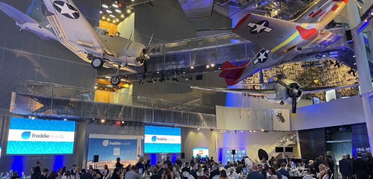 a group of people sitting at tables in a room with airplanes from ceiling