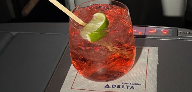 a glass of red liquid with a lime slice on a napkin