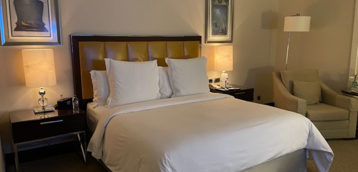 a bed with white sheets and a brown headboard in a hotel room