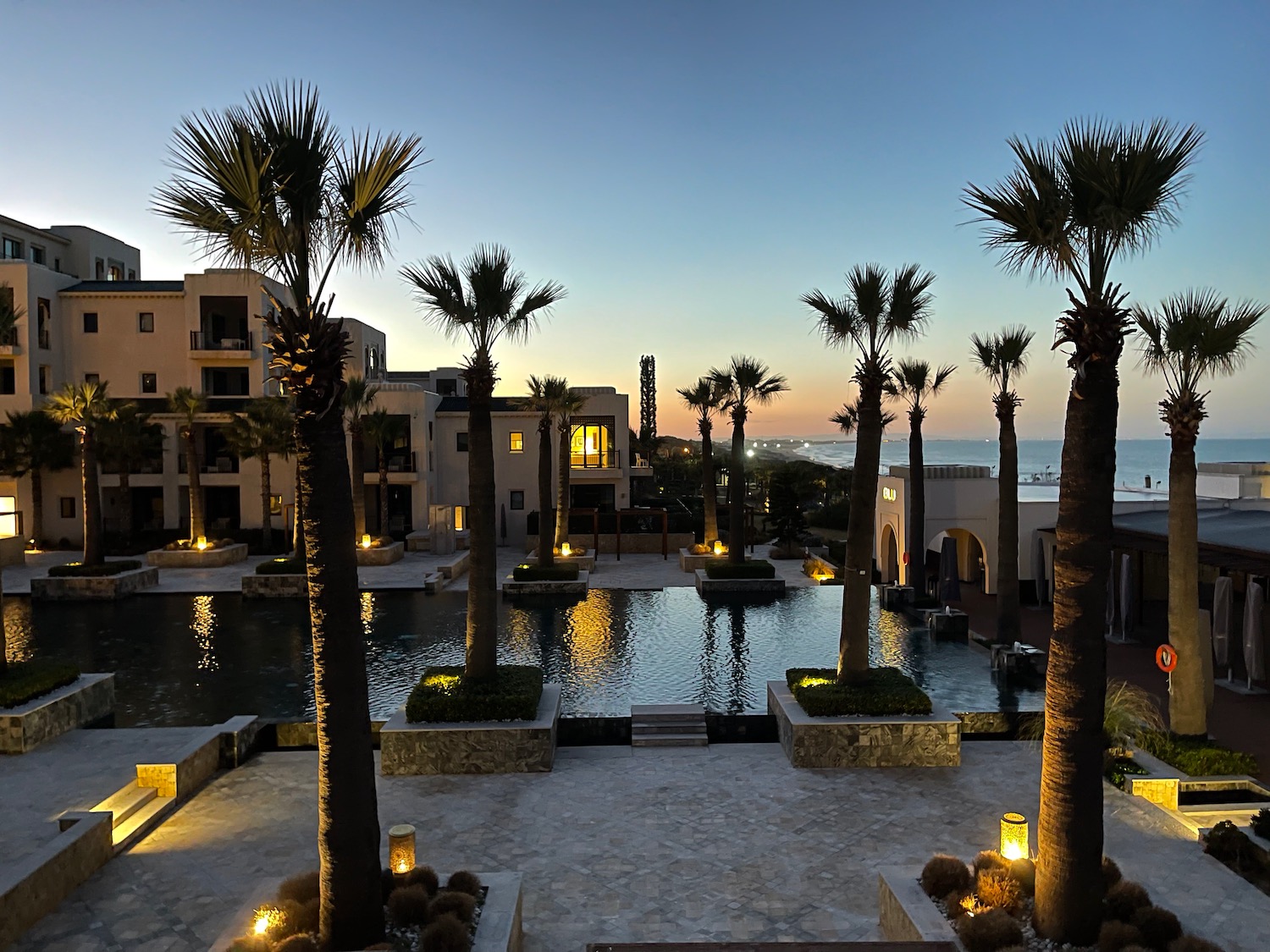 a pool with palm trees and buildings in the background