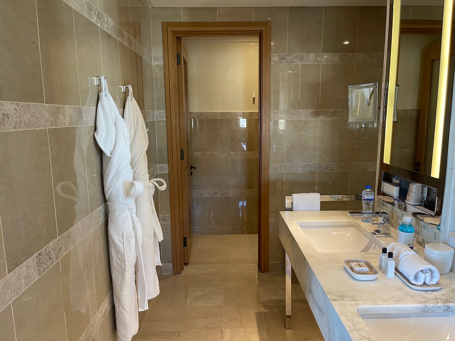 a bathroom with a door and two white bath robes