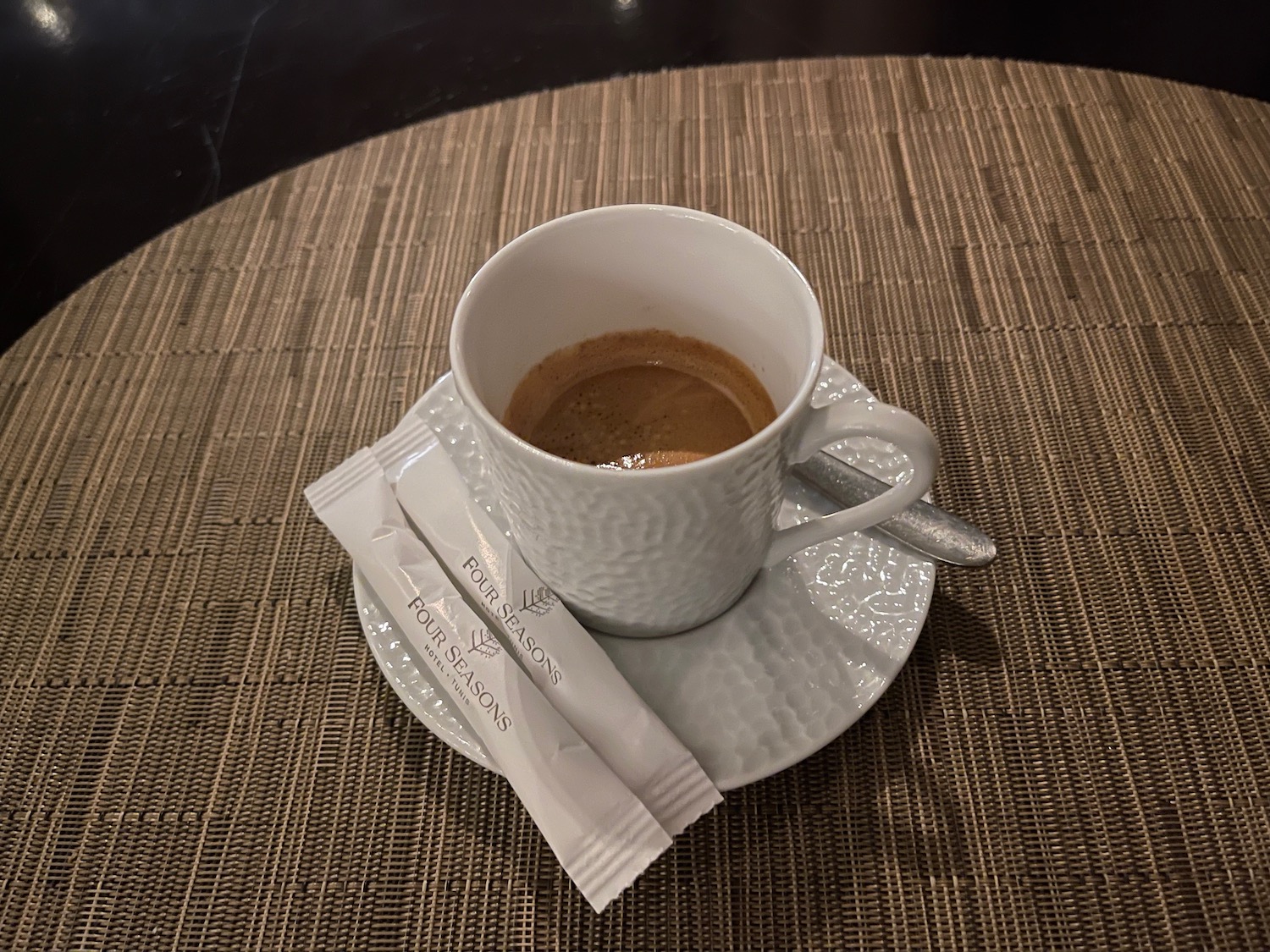 a cup of coffee on a saucer with a packet of sugar