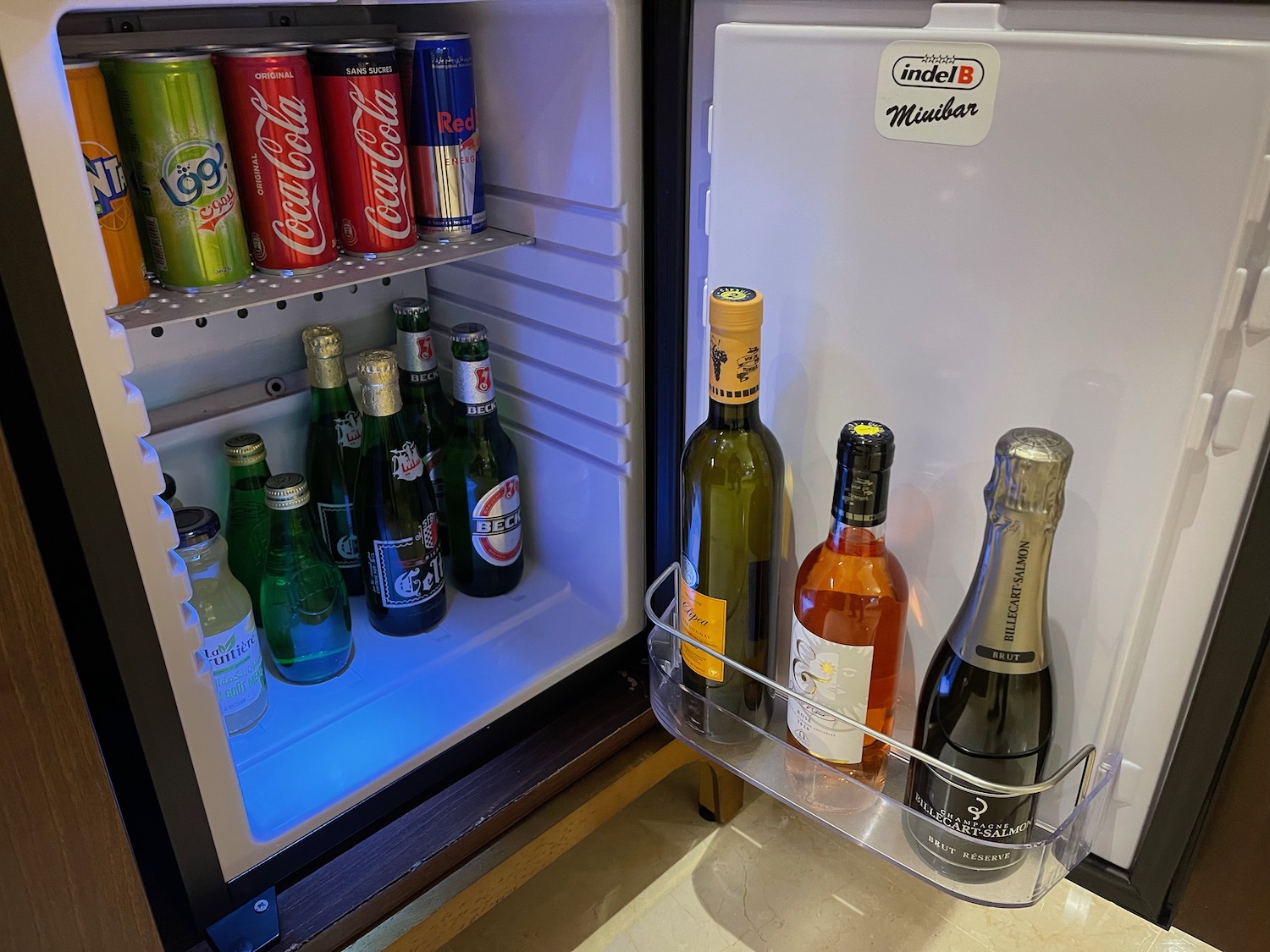 a mini fridge with bottles of alcohol and cans of soda