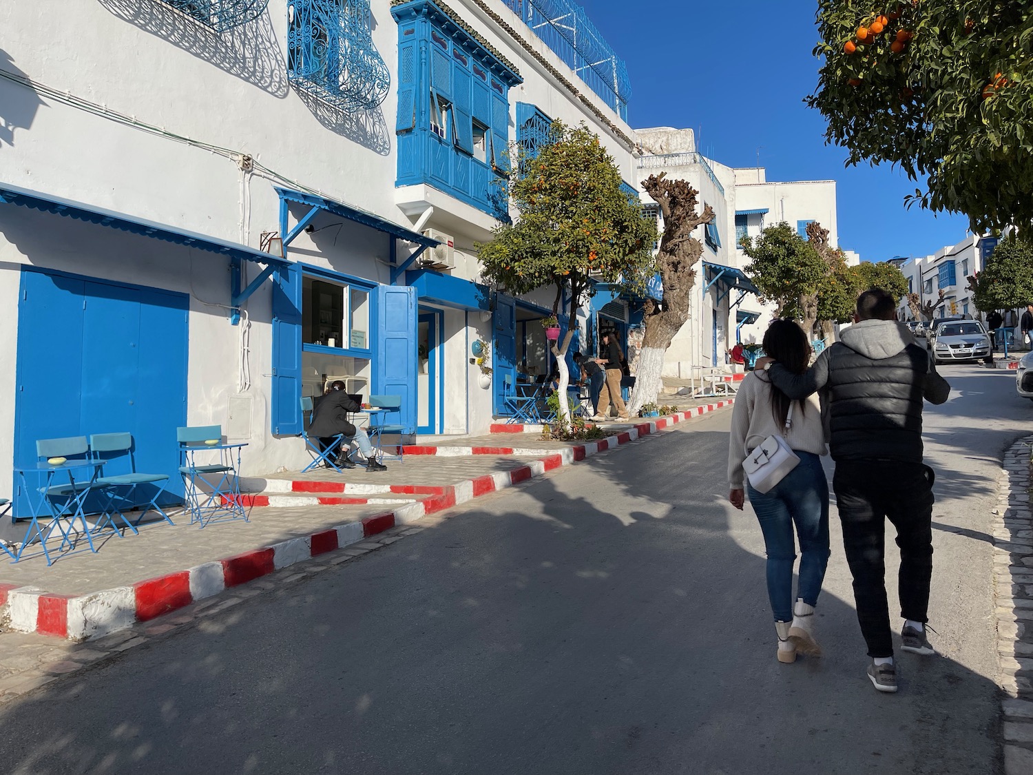 people walking down a street with blue and white buildings