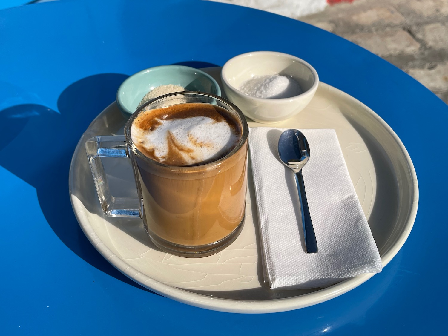 a cup of coffee with foam and a spoon on a plate