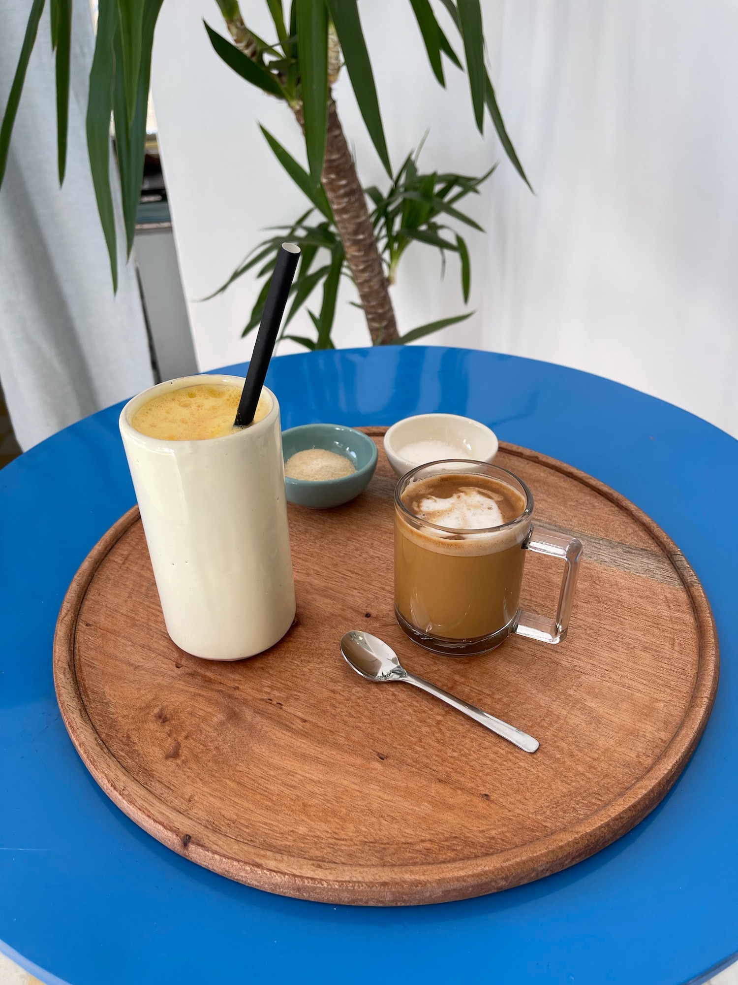 a wooden tray with a drink and spoon on it