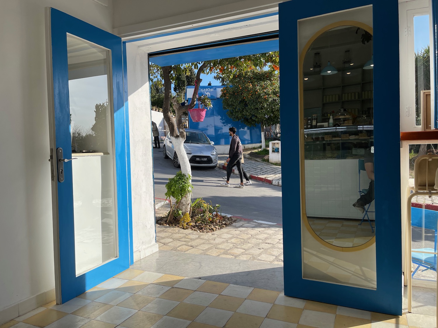 a blue doors with glass panels and a man walking on the street
