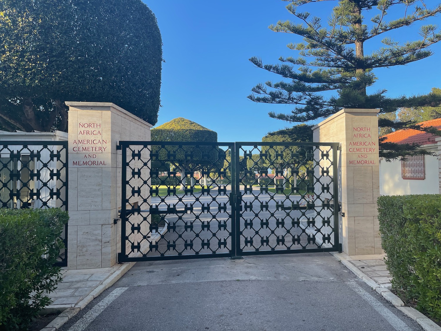 a gated driveway with trees and bushes