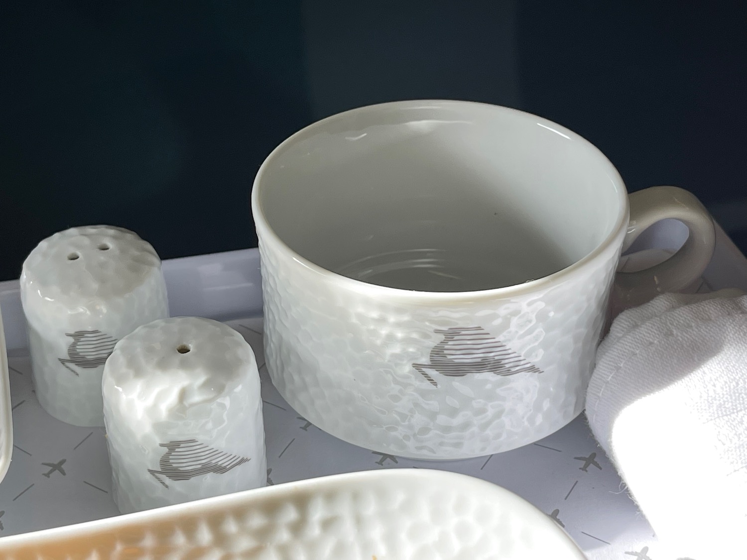 a white mug and salt shakers on a tray