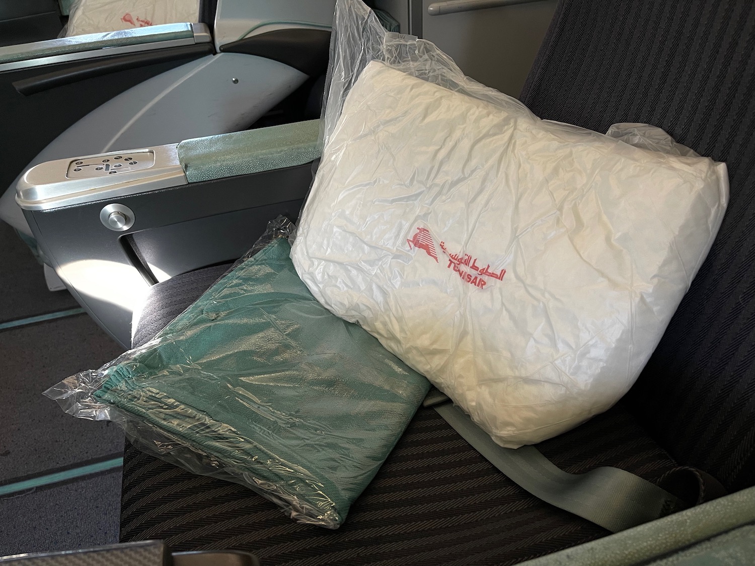 a white pillow and green pillow on a seat