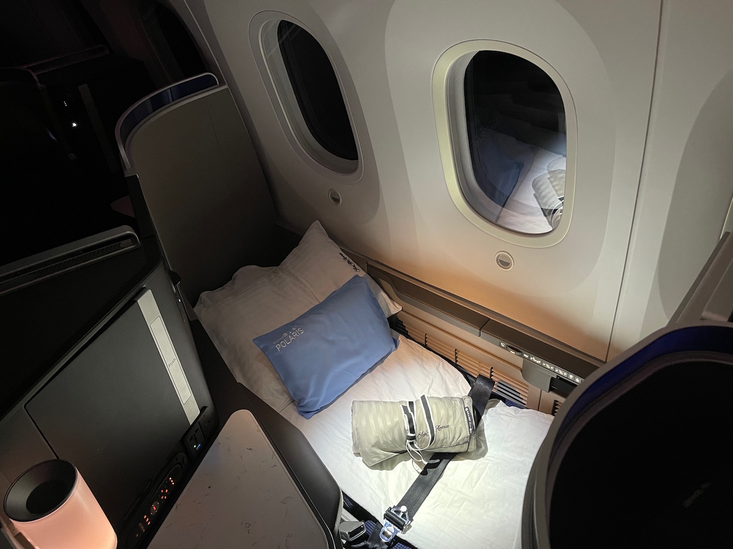 a bed with pillows and seat belts in an airplane