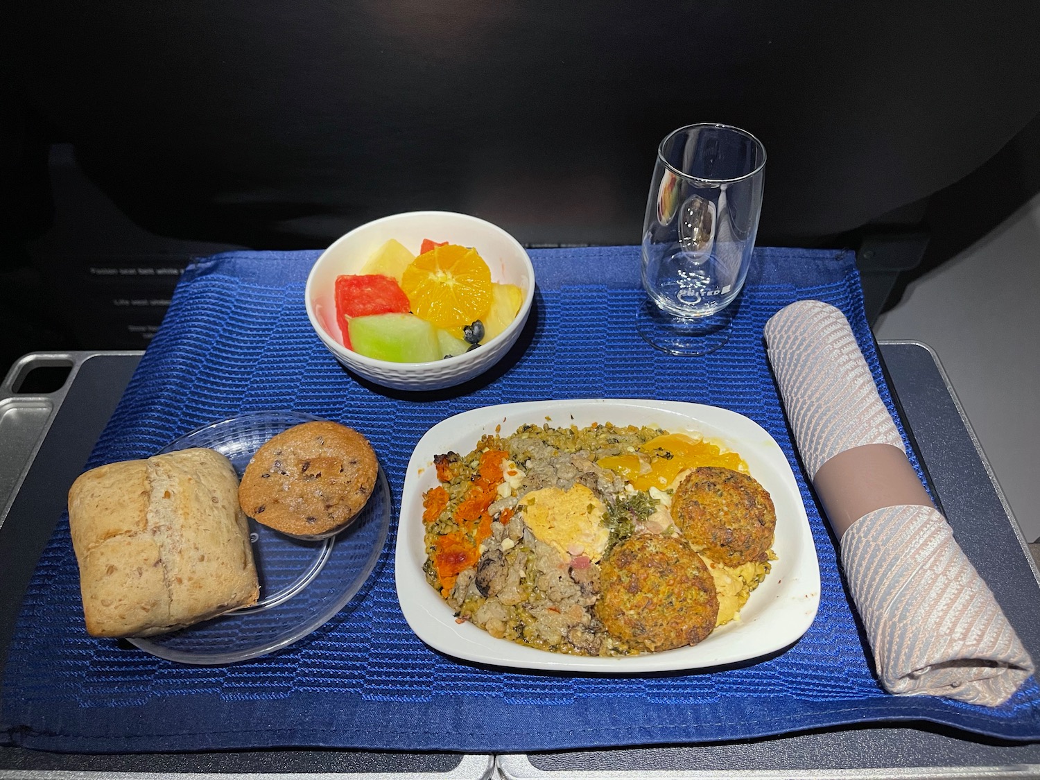 a plate of food and a glass on a blue place mat