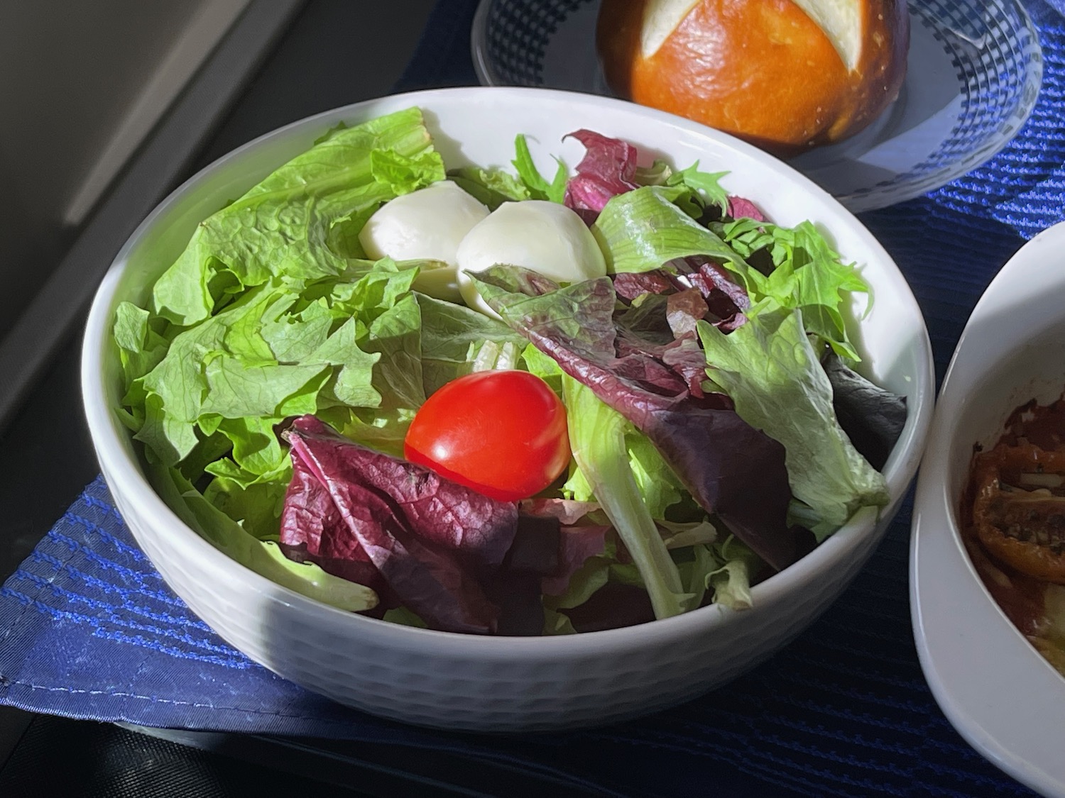 a bowl of salad with a tomato and cheese