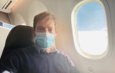 a man wearing a face mask sitting in an airplane