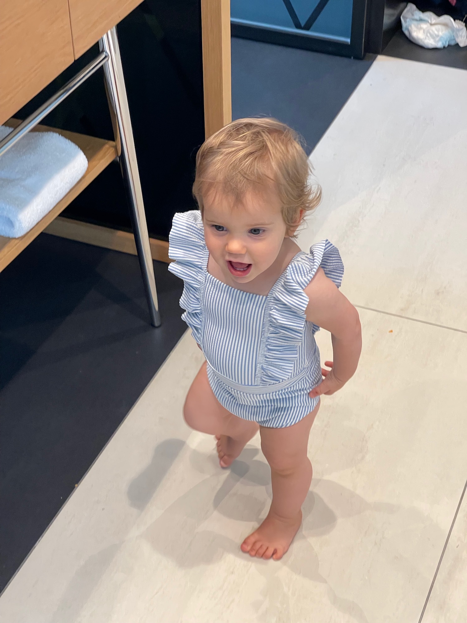 a baby girl standing on a tile floor
