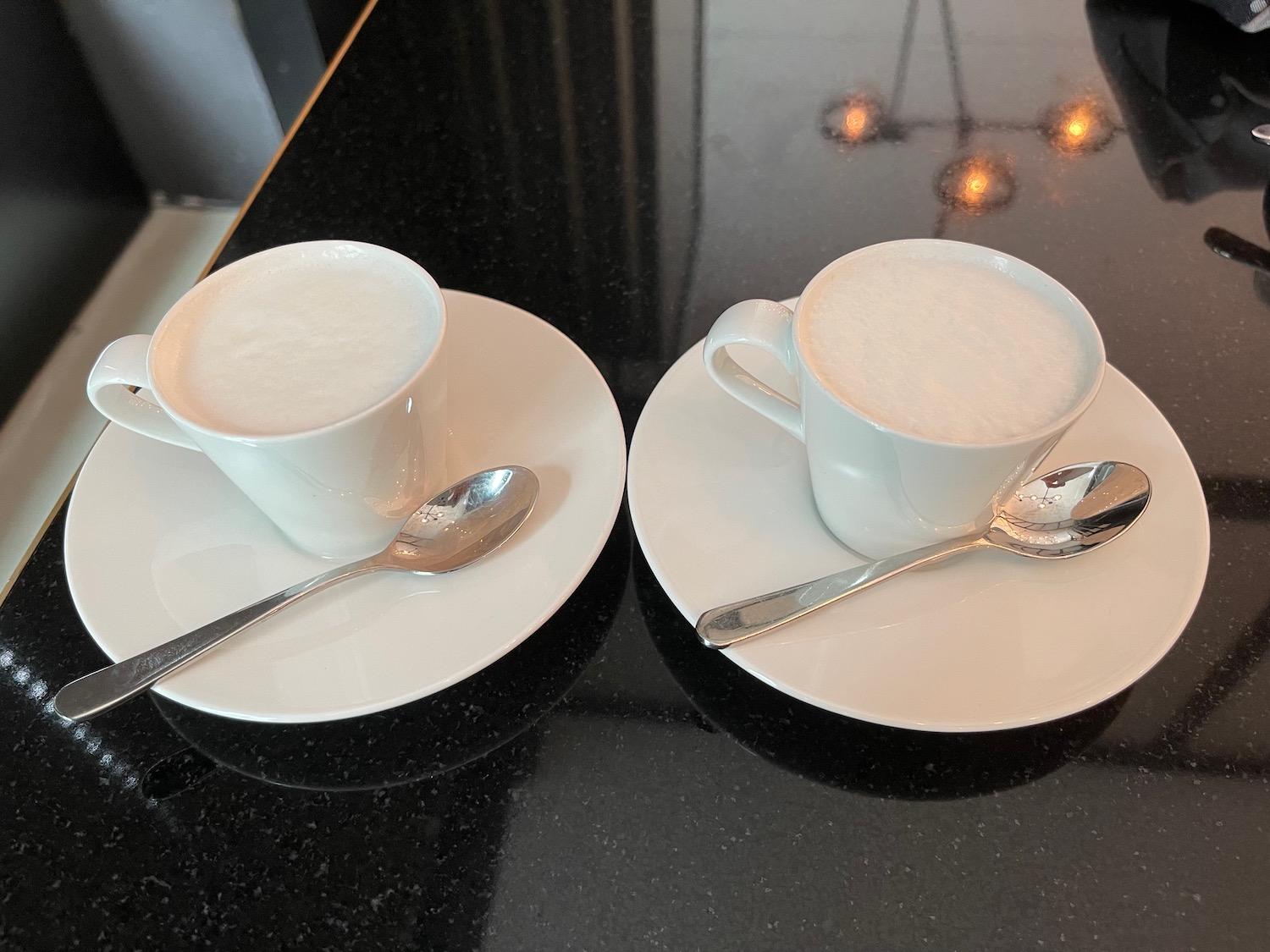 two cups of coffee on saucers with spoons